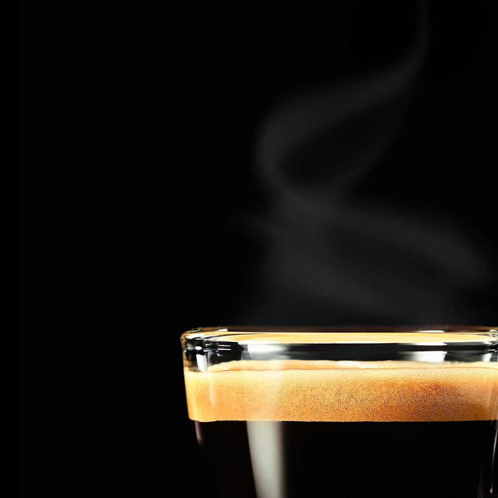 Taza de café solo con crema sobre fondo negro